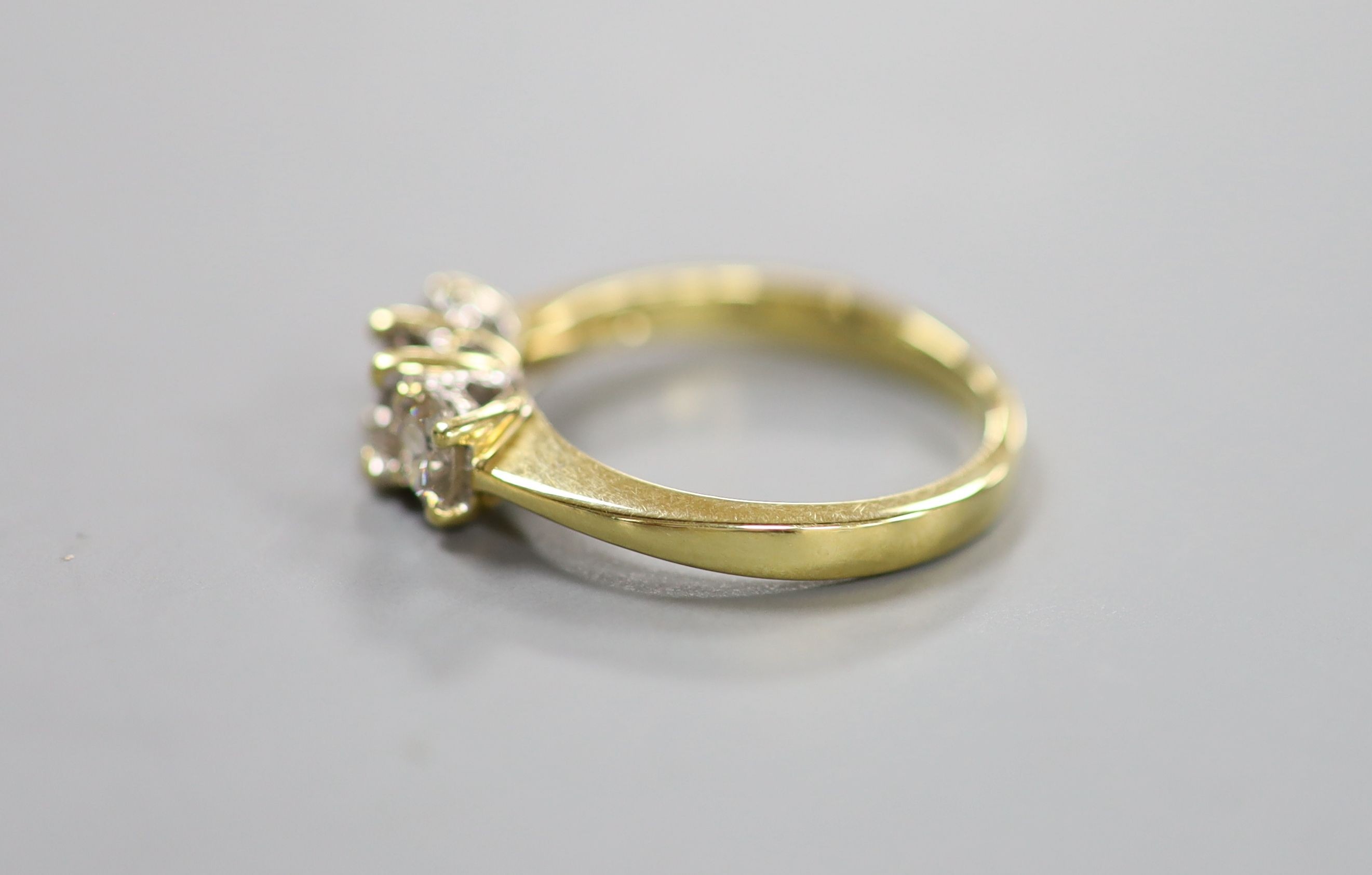 A modern 18ct gold and three stone diamond ring, size M, gross weight 3.4 grams.